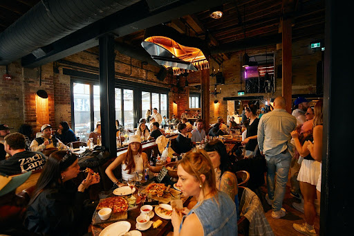 Busy dining room at The Parlour Toronto with guests enjoying pizza, cocktails, and nightlife energy on King West